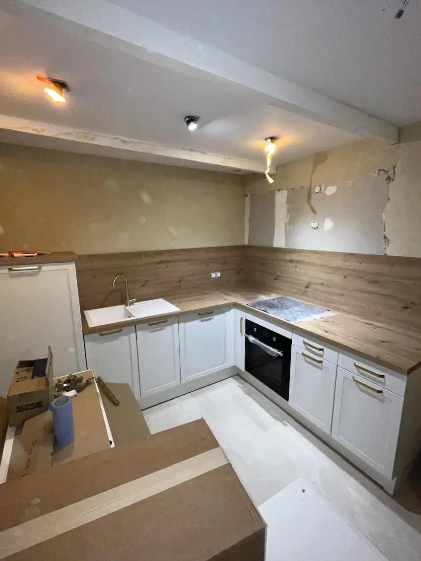 Cuisine équipée en cours d’installation : meubles bas, plan de travail bois, évier et four encastré raccordés