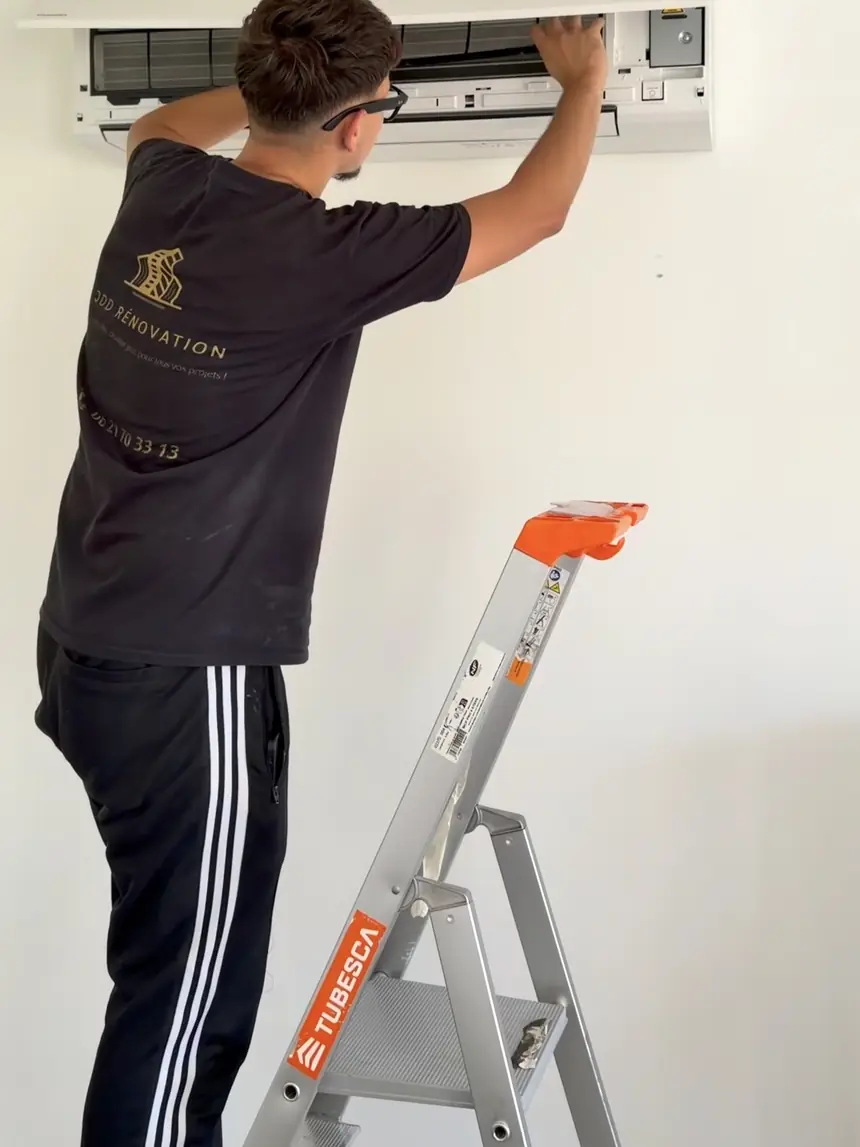 Technicien JDD Rénovation ouvrant l’unité intérieure d’une climatisation murale pour son entretien